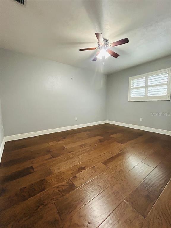 608 Southwest 80th Boulevard Gainesville, FL 32607 - Photo 21 of 25 an empty room with wooden floor and windows with curtains