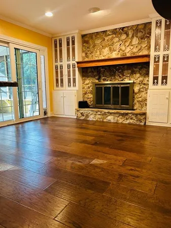 a view of an empty room with wooden floor and a fireplace