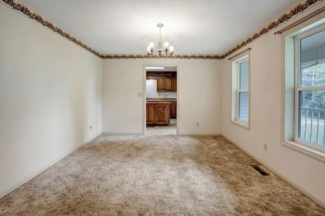 an empty room with chandelier and windows