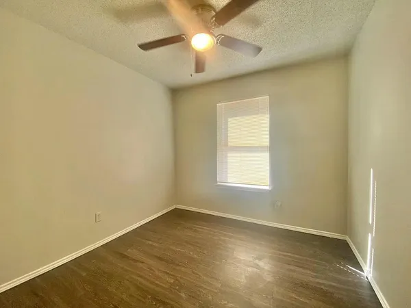 an empty room with a window and a fan