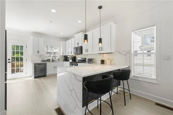 a kitchen with stainless steel appliances kitchen island a table chairs sink and cabinets