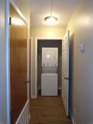 a view of a hallway with wooden floor and a bathroom