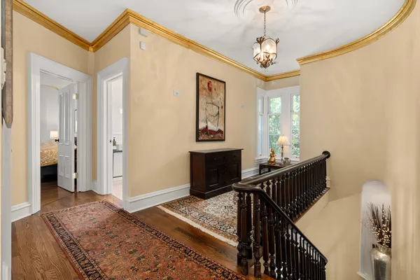 a view of a hallway to a livingroom with wooden floor and furniture