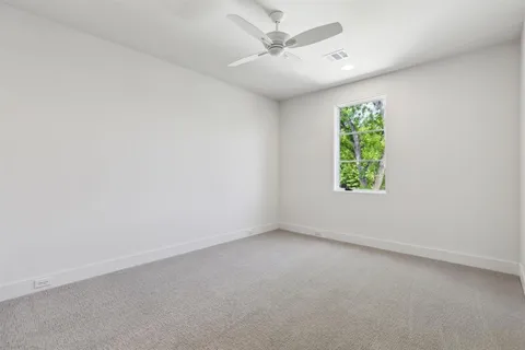 an empty room with a window and a ceiling fan