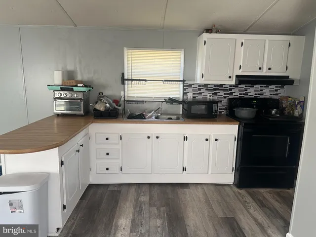 a kitchen with granite countertop a sink a stove and cabinets