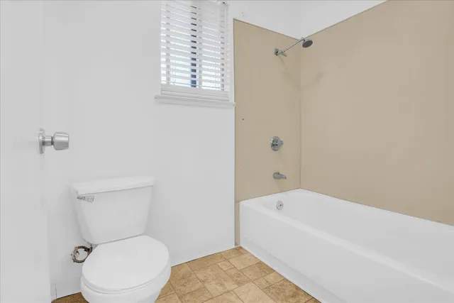 a white toilet sitting next to a bath tub