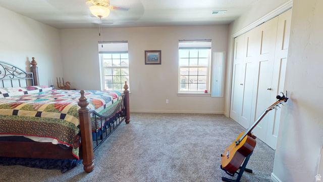 1674 Eastridge Road Price, UT 84501 - Photo 15 of 34 Bedroom featuring light neutral wall paint, two windows with gridded panes, a multi-panel closet with dual doors, and light gray carpeted flooring