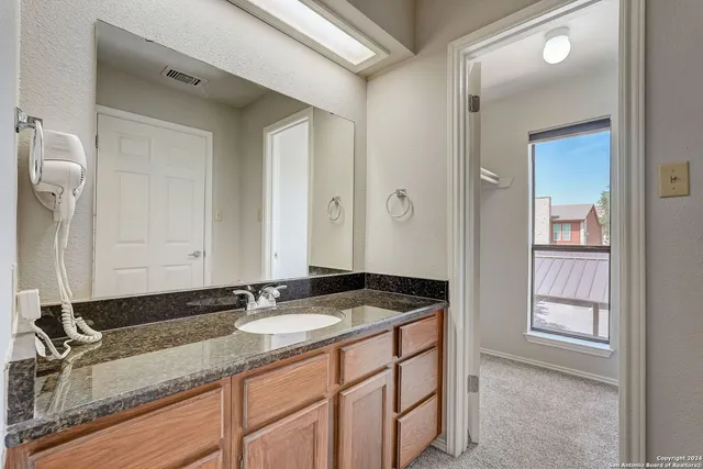 a bathroom with a granite countertop sink and a mirror