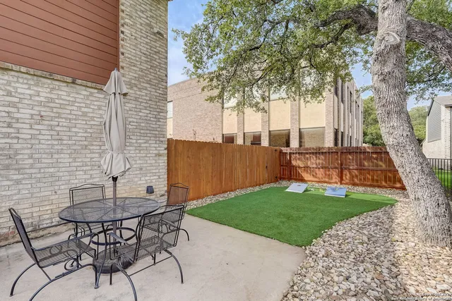 a view of a backyard with table and chairs and a barbeque with wooden fence