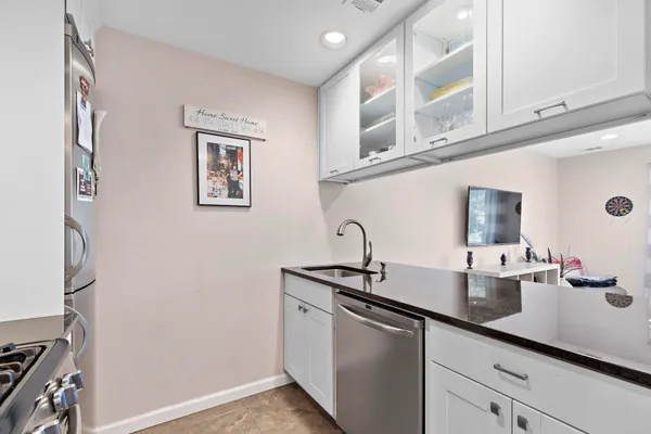 a kitchen with stainless steel appliances granite countertop white cabinets a stove top oven a sink and dishwasher