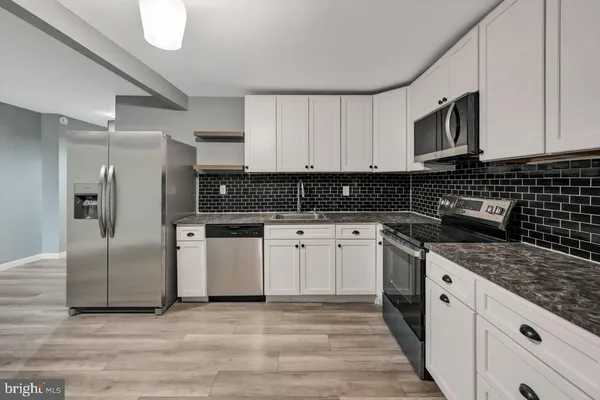 a kitchen with stainless steel appliances granite countertop a stove a sink and a refrigerator