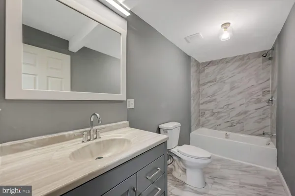 a bathroom with a granite countertop sink a toilet and bathtub