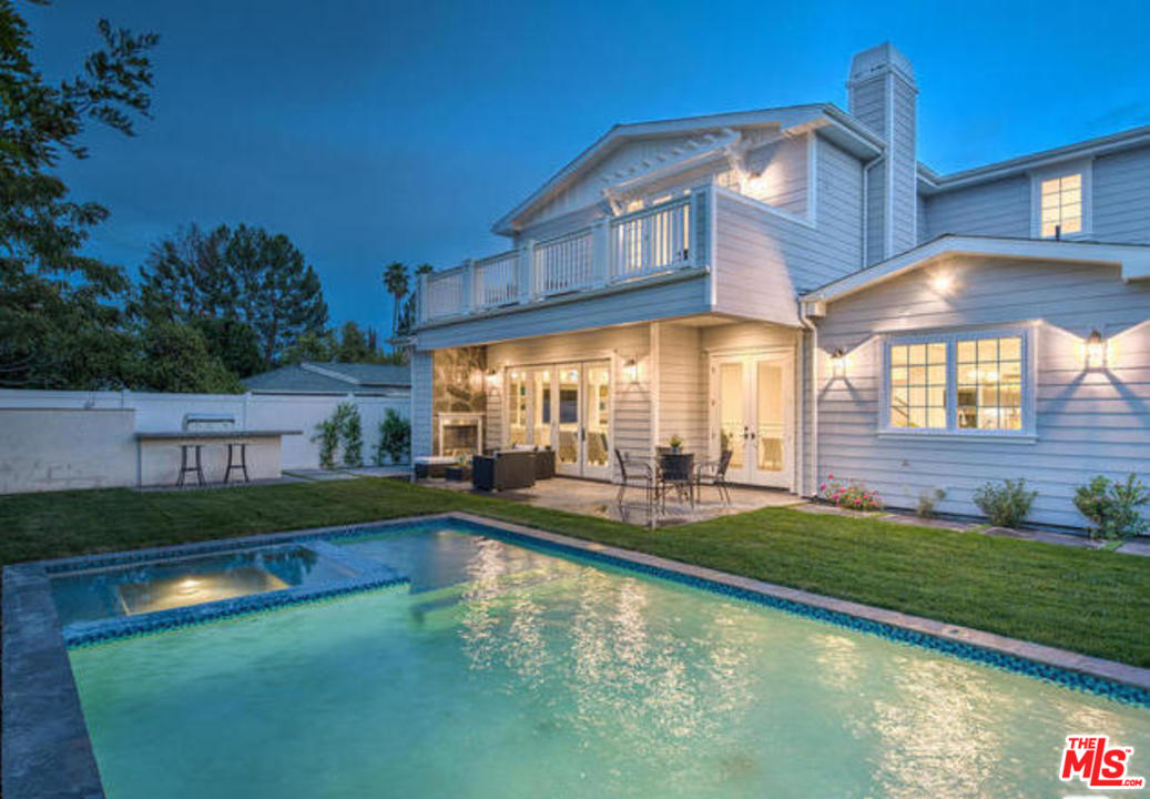a view of a house with swimming pool lawn chairs and a yard