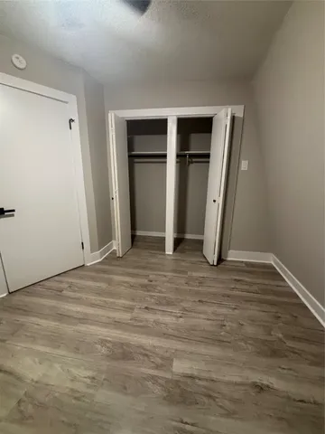 a view of an empty room with wooden floor and closet