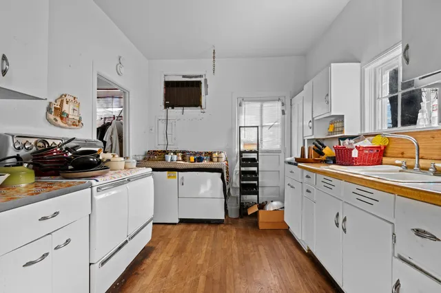 a kitchen with stainless steel appliances granite countertop a sink dishwasher stove and white cabinets with wooden floor
