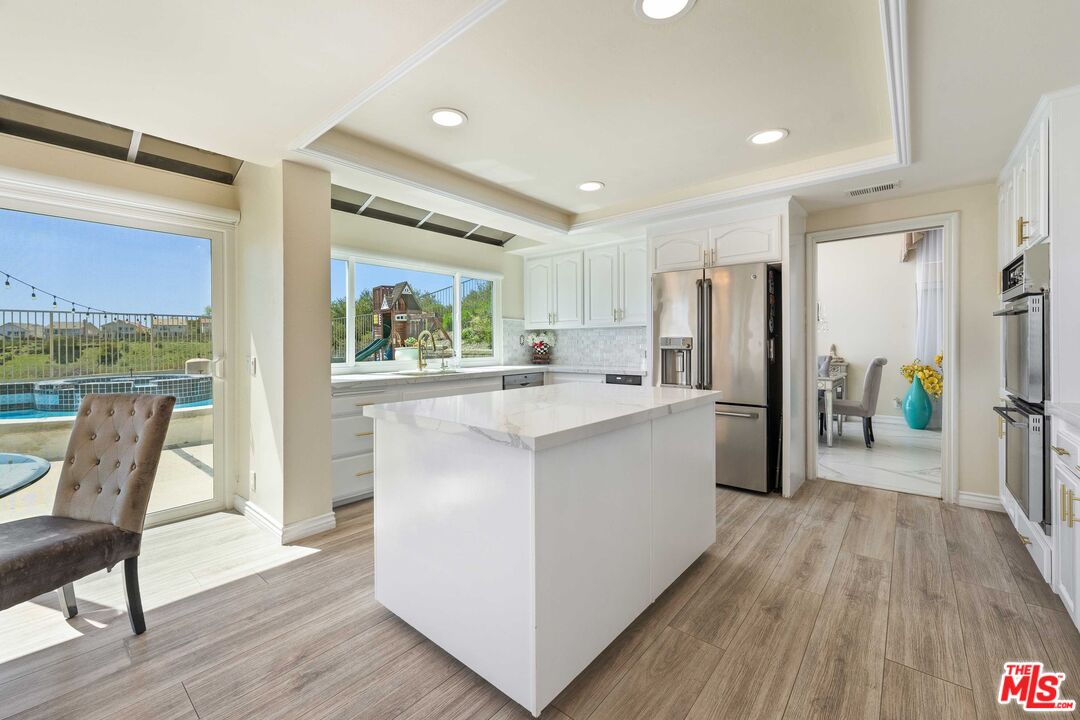19800 Winged Foot Way Porter Ranch, CA 91326 - Photo 9 of 48 a kitchen with stainless steel appliances a refrigerator a sink dishwasher a stove and a dining table with wooden floor