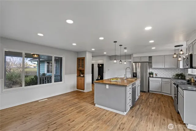 a kitchen with stainless steel appliances granite countertop a stove top oven and a refrigerator with wooden floor