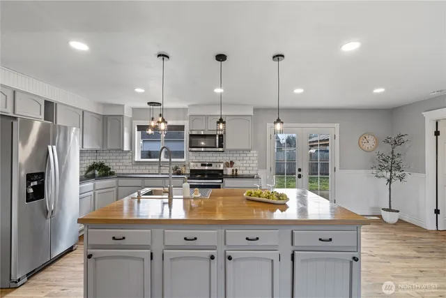 a kitchen with stainless steel appliances granite countertop a sink a stove and a refrigerator