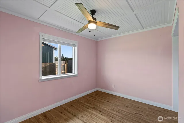a view of an empty room with a window and wooden floor