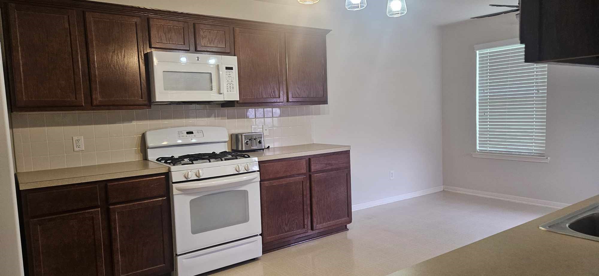 930 Sage Street Baytown, TX 77521 - Photo 18 of 27 a kitchen with stainless steel appliances granite countertop a stove a sink and a microwave