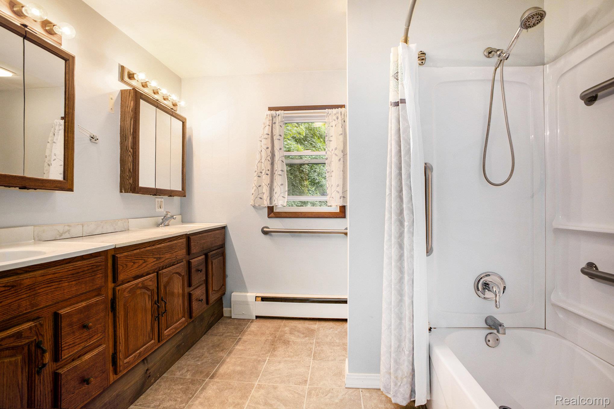 16568 28 Mile Road Albion, MI 49224 - Photo 19 of 26 Bathroom with shower / bathtub combination with curtain, double vanity, baseboard heating, and light tile patterned floors