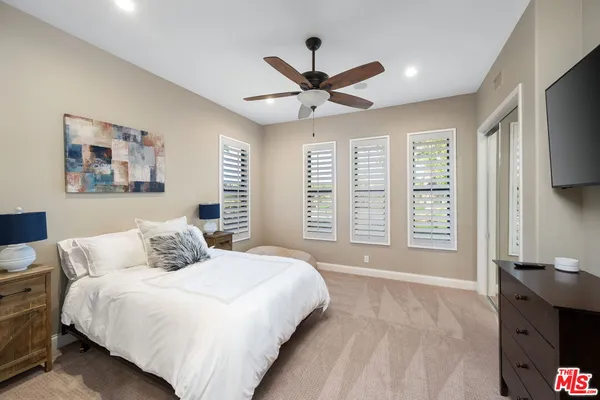 a bedroom with a large bed and a flat tv screen on dresser