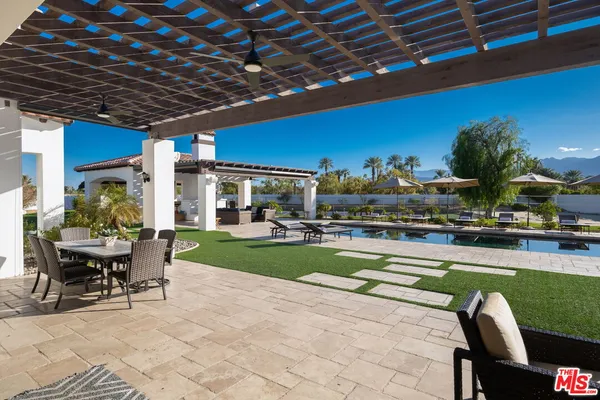 a view of a swimming pool and couches in patio with a yard