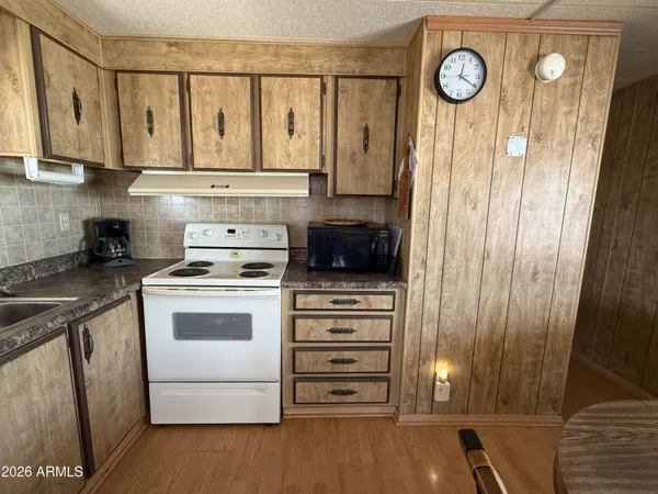 a kitchen with stainless steel appliances granite countertop a refrigerator a stove oven a sink dishwasher and white cabinets with wooden floor