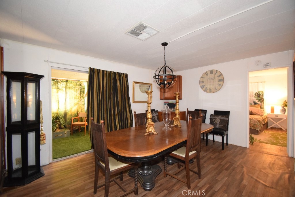 7425 Church Street, Unit 10 Yucca Valley, CA 92284 - Photo 11 of 24 a view of a dining room and livingroom with furniture wooden floor a rug a potted plant and a chandelier