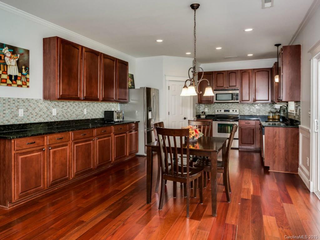 306 Allspice Road Fort Mill, SC 29708 - Photo 3 of 24 a kitchen with stainless steel appliances wooden floors wooden cabinets dining table and chair