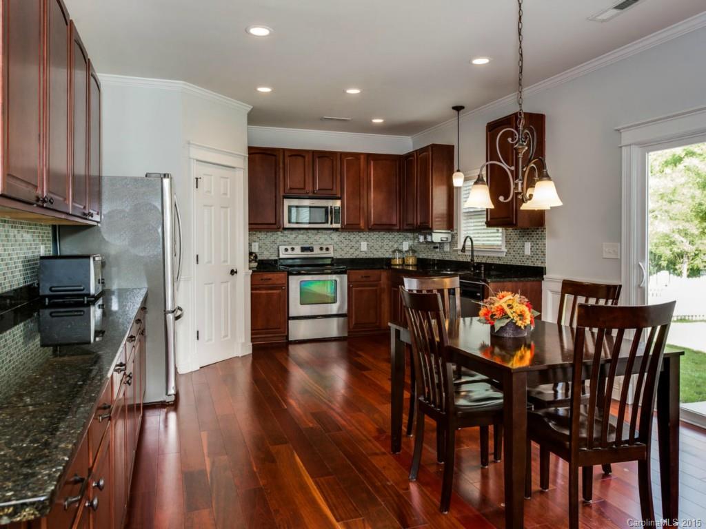 306 Allspice Road Fort Mill, SC 29708 - Photo 4 of 24 a kitchen with stainless steel appliances granite countertop a stove top oven a refrigerator a sink and a dining table with wooden floor