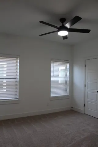 an empty room with a window and ceiling fan