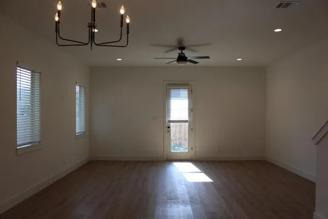 an empty room with wooden floor and windows