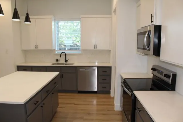 a kitchen with a sink dishwasher a stove and a refrigerator with wooden floor