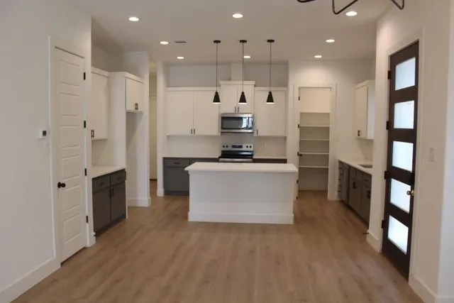 a large kitchen with stainless steel appliances kitchen island a large counter top and a refrigerator