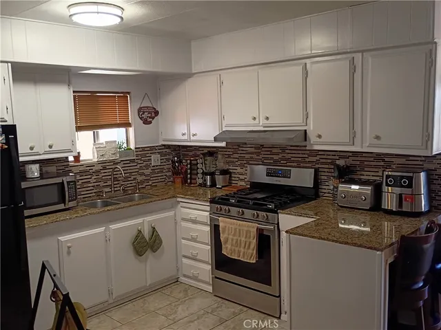 a kitchen with stainless steel appliances granite countertop a stove a sink and a microwave