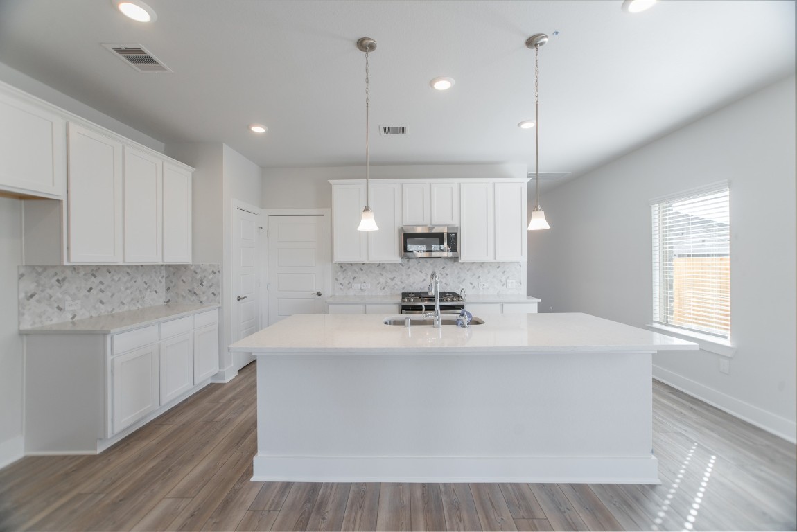 10627 Whitejacket Conroe, TX 77385 - Photo 11 of 46 a large white kitchen with kitchen island a sink a center island a stove and a window