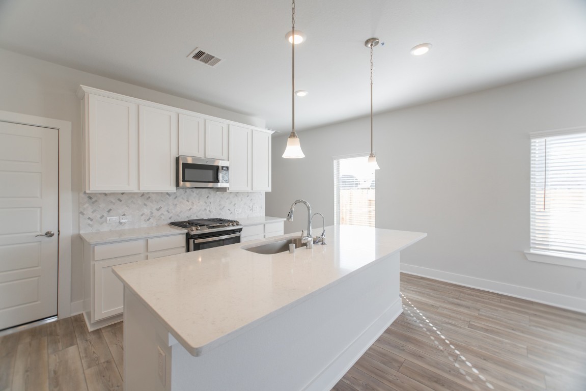 10627 Whitejacket Conroe, TX 77385 - Photo 12 of 46 a kitchen with a sink a stove a microwave and wooden floor