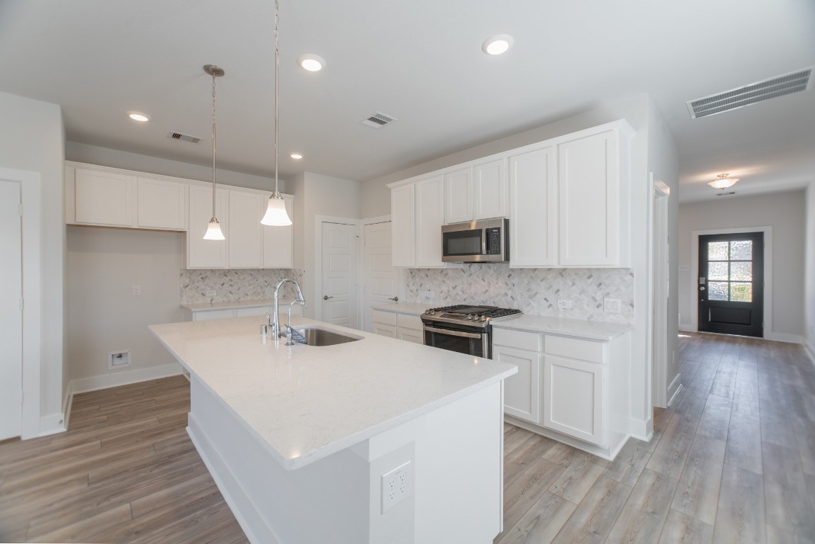 10627 Whitejacket Conroe, TX 77385 - Photo 10 of 46 a kitchen with stainless steel appliances kitchen island granite countertop a stove a sink a refrigerator and white cabinets with wooden floor