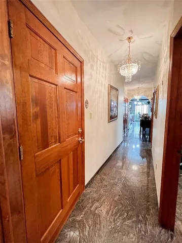 a view of a hallway with wooden floor and chandelier