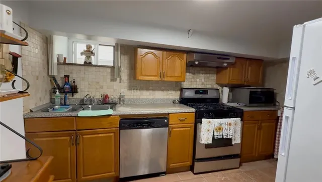 a kitchen with stainless steel appliances granite countertop a stove a sink and a microwave