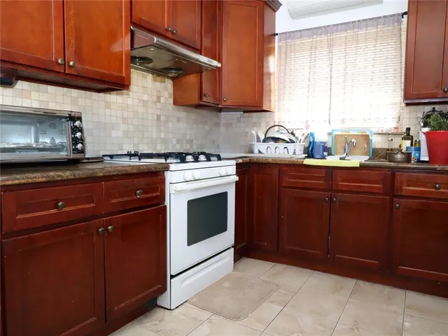 a kitchen with granite countertop wooden cabinets and a stove top oven