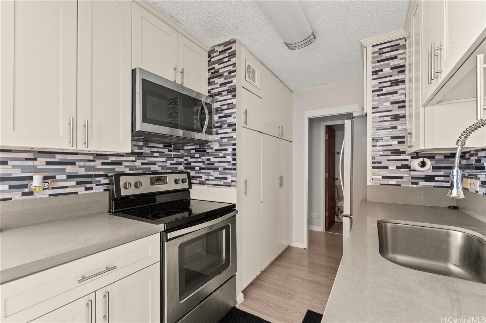 1069 Spencer Street, Unit 101 Honolulu, HI 96822 - Photo 3 of 19 a kitchen with stainless steel appliances a stove a microwave and a counter space