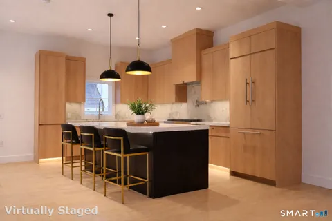 a kitchen with stainless steel appliances kitchen island granite countertop a table chairs and a refrigerator