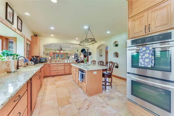 a large kitchen with stainless steel appliances granite countertop a stove and a view of living room