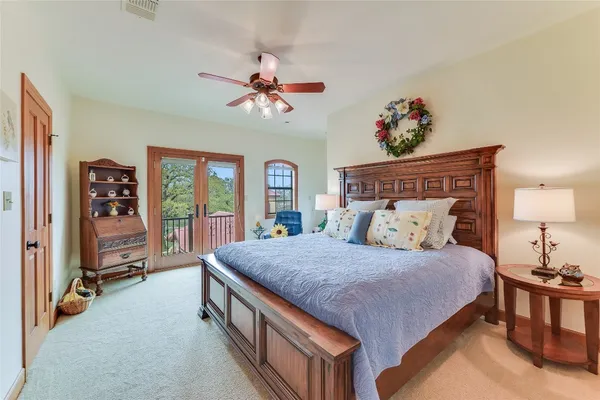 a spacious bedroom with a bed a dresser and a chandelier
