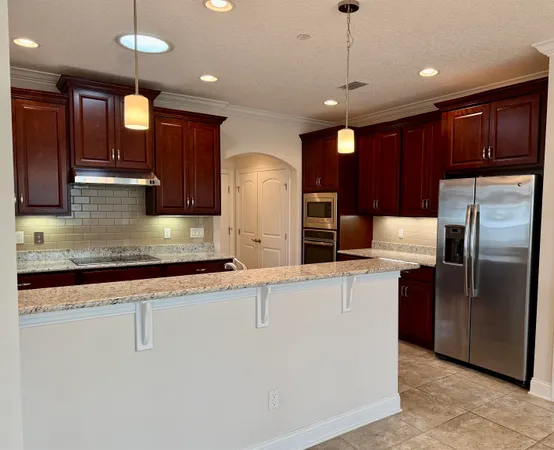 a large kitchen with stainless steel appliances granite countertop a refrigerator a oven and a sink with granite countertops