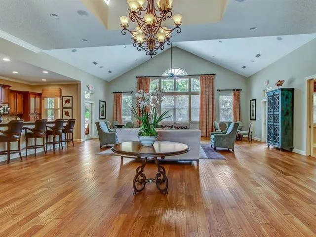 a living room with pool table furniture a flat screen tv and a chandelier