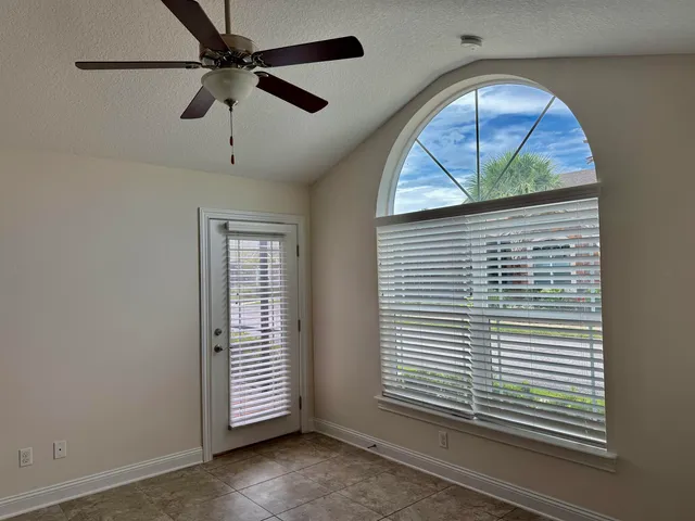 an empty room with wooden floor chandelier fan and windows