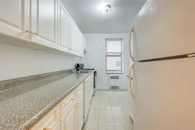 a view of a kitchen with white cabinets and refrigerator